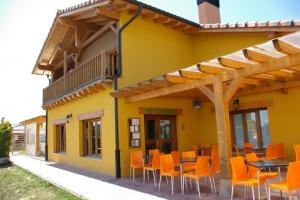 Camping El Roble Verde的黄色的建筑,配有橙色的椅子和桌子