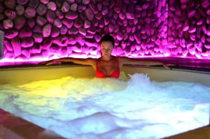 基安奇安诺泰尔梅Hotel Del Buono Wellness & Medical Spa的紫色灯浴缸中的女人
