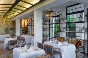 卢萨卡Ciêla, Lusaka, Tribute Portfolio Resort and Spa的餐厅设有白色的桌椅和窗户。