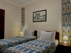 布哈拉Hotel Saidkasim with a Terrace的酒店客房设有两张床,墙上挂着一张照片。