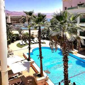 埃拉特Milana's Deluxe with big patio and pool的棕榈树和游泳池度假村