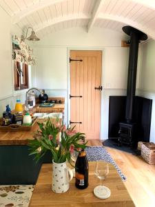 霍尔斯沃西Lilliput - Delightful 1-bedroom shepherd's hut的厨房配有带葡萄酒玻璃和炉灶的桌子。