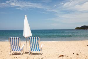 稻克稻克格兰德Refúgio Toque Toque Chalés的海滩上的两把椅子和一把遮阳伞