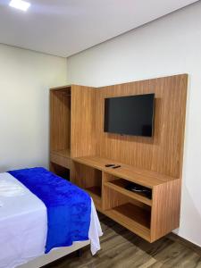 皮乌米Chalés Vista da Serra的一间卧室配有一张床,墙上配有电视