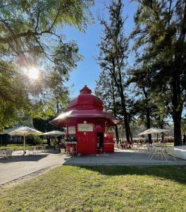 里斯本The Swallows Nest的公园里红色的电话亭,配有桌子和雨伞