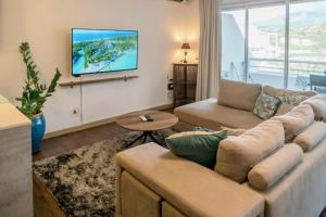 帕皮提Grand Large - Premium suite的客厅配有沙发和墙上的电视