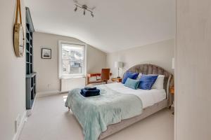 伦敦Boutique Victorian 4 Bed House with Garden in Balham的一间卧室配有一张带蓝色枕头的床和电视。