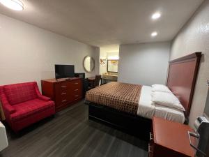 琼斯伯勒Scottish inns Jonesboro的酒店客房,配有一张床和一张红色椅子