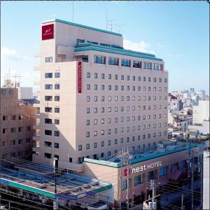 松山松山奈斯特酒店的一座白色的大建筑,上面有红色的标志