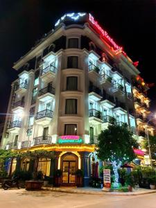 下龙湾Halong Boutique Hotel的一座白色的大建筑,晚上有灯