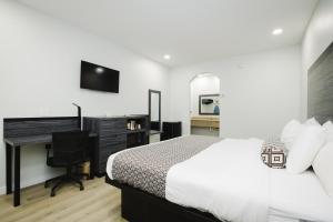 迪尔帕克Sapphire Inn & Suites的一间卧室配有一张床、一张书桌和一台电视