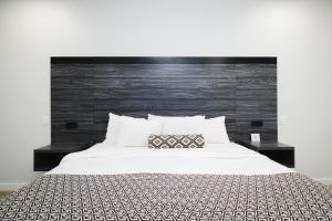 迪尔帕克Sapphire Inn & Suites的一间卧室配有一张白色的床和黑色床头板