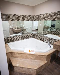 Bell贝尔钻石套房酒店的一个带大浴缸的浴室,配有两个盥洗盆