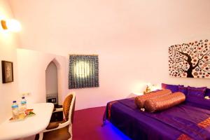 吉利阿尔Bel Air Resort的一间卧室配有一张紫色的床、一张桌子和一张桌子