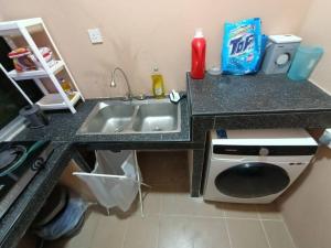 山打根HS Homestay的厨房柜台设有水槽和洗衣机。