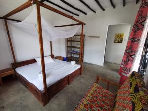 南威EAST SANDBANK apartment eco-friendly Nungwi airport road的一间卧室配有天蓬床和沙发