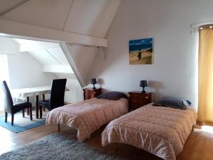 奥雷龙圣但尼因素莱尔旅馆的一间卧室配有两张床和一张桌子及椅子