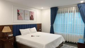 宁平Tam Coc Center Boutique Hotel的一间卧室配有一张带蓝色窗帘的床和一扇窗户