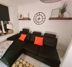 锡厄姆The Light House的客厅配有带橙色枕头的黑色沙发