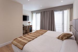 坎普罗东Hotel SAIOLA的卧室配有一张白色大床和一张书桌