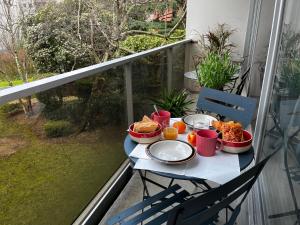 布洛涅-比扬古Spacieux studio sur jardin, beaucoup de charme的阳台上的桌子上摆放着食物和饮料