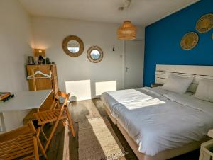 弗劳温普尔德Budget Hotel Vrouwenpolder的一间卧室设有蓝色的墙壁、一张床和一张书桌