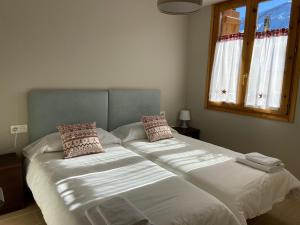 潘蒂科萨Apartamento Casa Francho 3的一间卧室设有两张带白色床单的床和窗户。