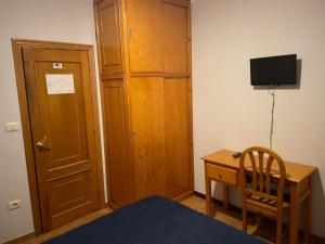 奥伦塞HOSTAL CID的一间卧室配有木制橱柜和一张书桌及电视