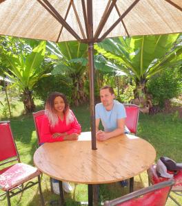 纳库鲁Homebase gardens的坐在桌子下伞下的男人和女人