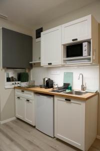 布达佩斯阿卡法假日公寓的厨房配有白色橱柜和水槽