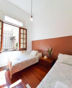 布宜诺斯艾利斯LOPEZ Hostel & Suites的一间卧室设有两张床和窗户。