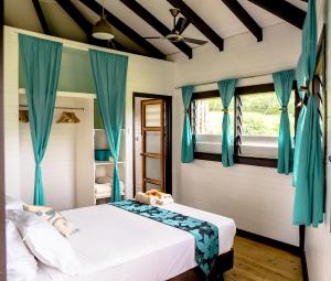 马太Vakanananu Retreat的一间卧室配有一张带蓝色窗帘的大床