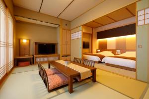 琴平町Onyado Shikishima-kan的酒店客房带两张床、一张桌子和一间卧室