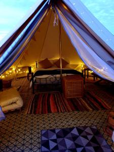 滨海索尔特本Luxury 5m bell tent with log burner near Whitby的帐篷,配有带灯的床铺