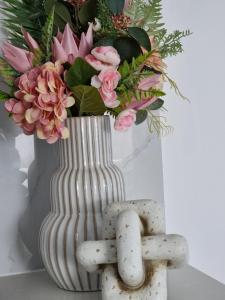 洛甘利The Lux Guest House的白色花瓶,花粉和一些岩石