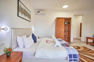 南威Malika Nungwi Hotel的卧室配有白色的床和木制橱柜。