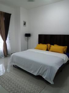 哥打丁宜Madinatus Syifa Homestay的卧室配有一张带黄色枕头的大型白色床。