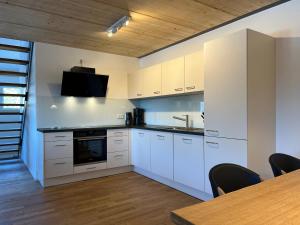 费尔德伯格Haus Wiesenquelle, Deluxe-Apartment 'Feld & Berg'的厨房配有白色橱柜和桌椅