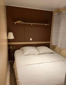 拉罗克当泰龙Mobil-Home des Iscles的卧室内的一张带白色床单和枕头的大床