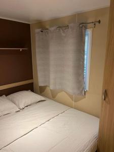 拉罗克当泰龙Mobil-Home des Iscles的一间卧室配有床和带窗帘的窗户