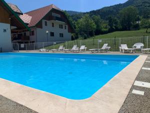 日耶Petit cocon entre lac, golf et montagne, proche d'Annecy的一个带椅子的蓝色游泳池以及一座房子