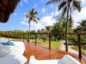 托弗海滩Kumba Lodge的一个带白色家具和棕榈树的木甲板