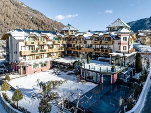 科姆梅扎杜拉Tevini Dolomites Charming Hotel的一座大建筑,地面上积雪