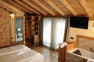利维尼奥赫尔维蒂酒店的一间卧室配有一张床、一台电视和一个浴缸