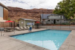 摩押Sun Outdoors North Moab的一个带椅子的游泳池以及一座房子