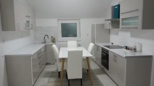 布尔奇科Apartman XXL的白色的厨房配有桌椅