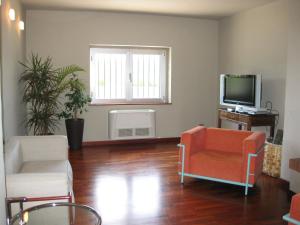卡迈格拉特罗希拉诺圣洛伦索斯艾柏佳酒店的客厅配有两把椅子和电视