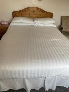 约克Diamonds Inn的一张白色的床,配有木制床头板和白色床单