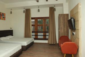 MadhupurThe Stoneberry Resort的一间卧室设有两张床、一台电视和一扇窗户。