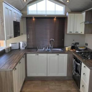 莫珀斯Lemon Tree Lodge的厨房配有白色橱柜、水槽和窗户。